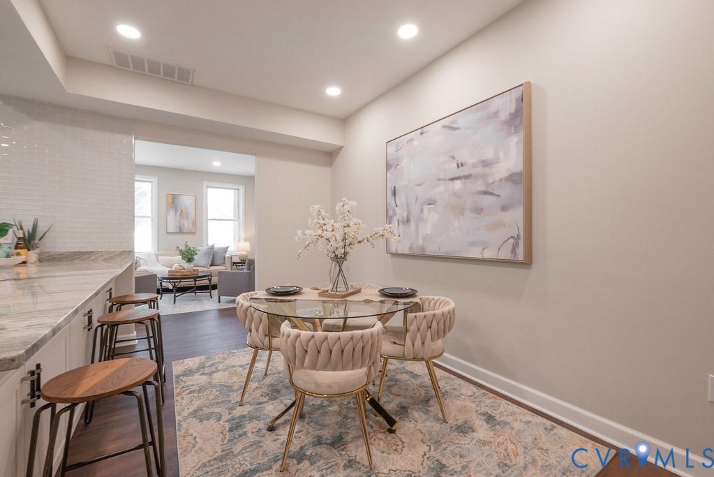 Recessed lighting illuminates wood-finish flooring, a kitchen peninsula with a stone countertop, and a white subway tile backsplash