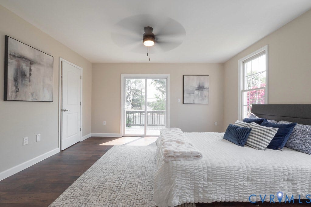 Wood-finish flooring, ceiling fan, white trim, sliding glass door with deck access, and double-hung windows