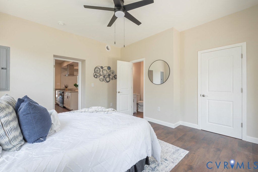 Hardwood-style flooring, white paneled doors, and a ceiling fan with integrated lighting