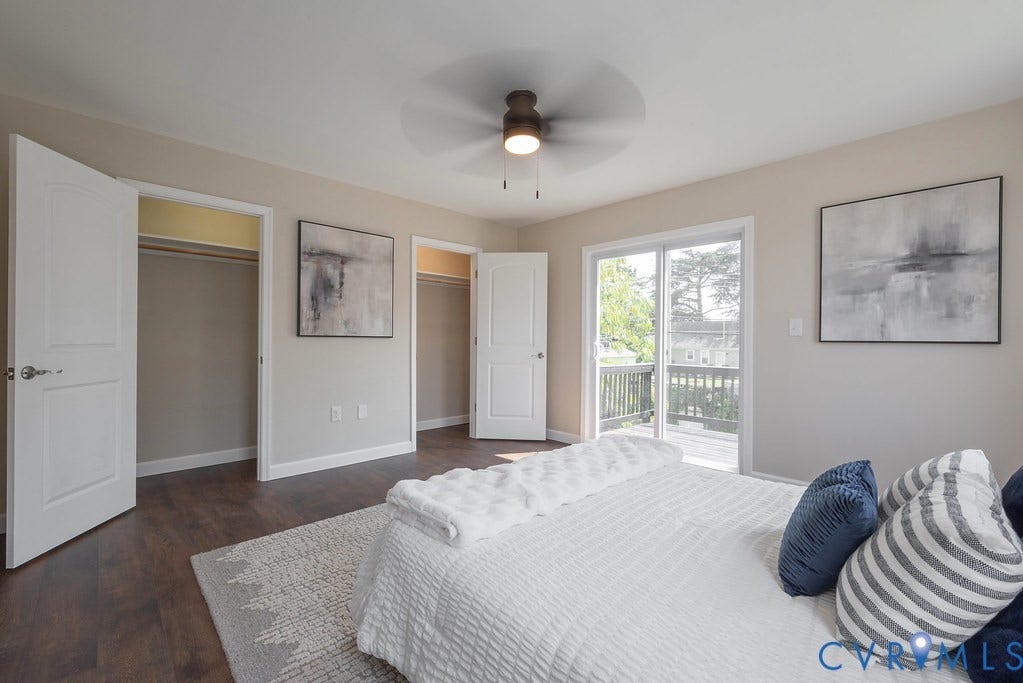 Wood-finish flooring, sliding glass door to exterior deck, two built-in closets, and a ceiling fan with integrated lighting