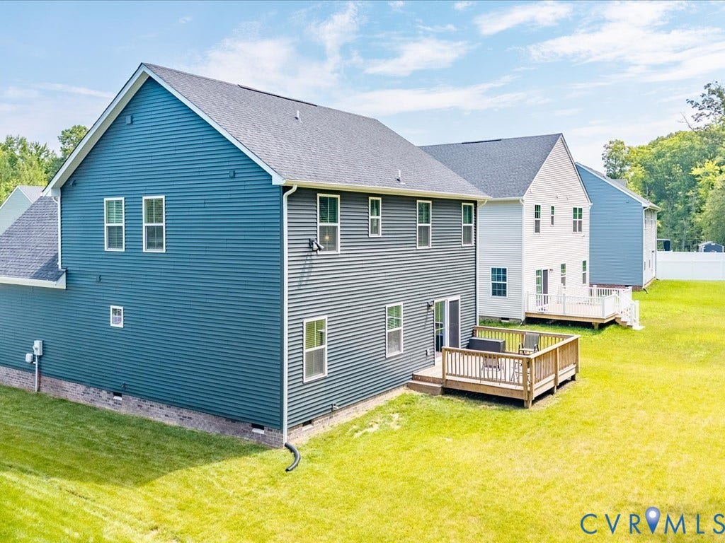 Exterior featuring blue and gray siding, multiple windows, a wooden deck, and a green lawn