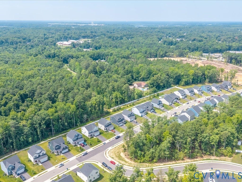 Residential development featuring contemporary homes with paved driveways, surrounded by extensive mature trees