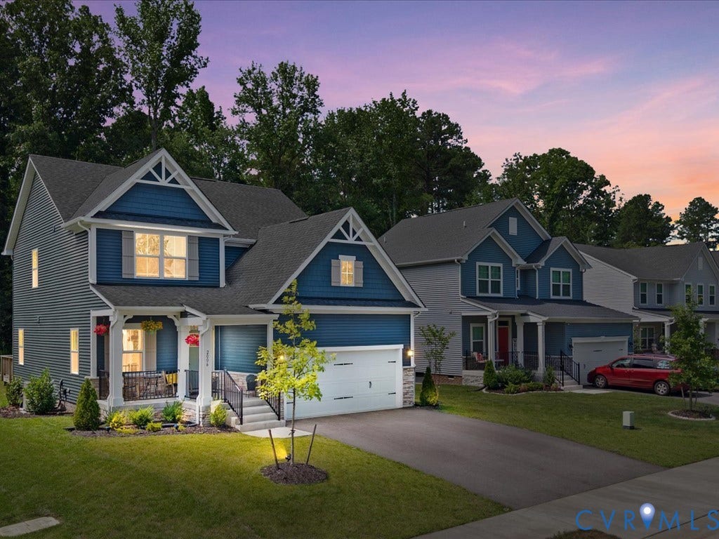 Two-story residence featuring blue siding, a covered front porch, and a two-car garage