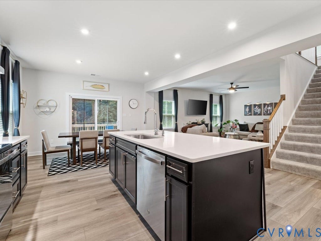 Kitchen featuring an island with a built-in sink, stainless steel appliances, and wood-finish flooring