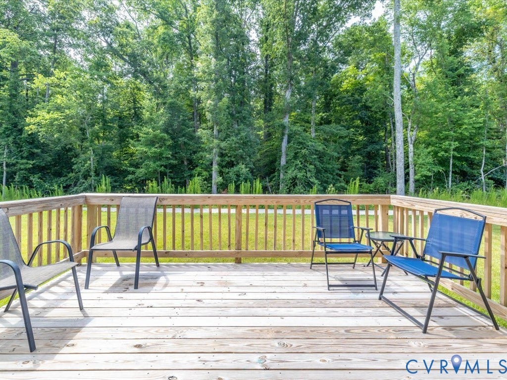 Expansive wood deck with a full wood railing overlooking a grassy yard with mature trees