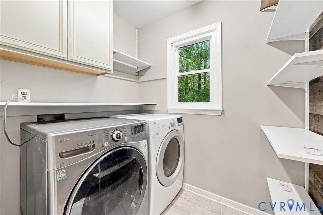 4106 Gloucestershire Street, North Chesterfield, VA 23236 Modern laundry room featuring stainless steel front-load washer and dryer with digital controls, white cabinetry with wood-finish accents, quartz countertop workspace, recessed lighting, and a transom window providing natural light and ventilation