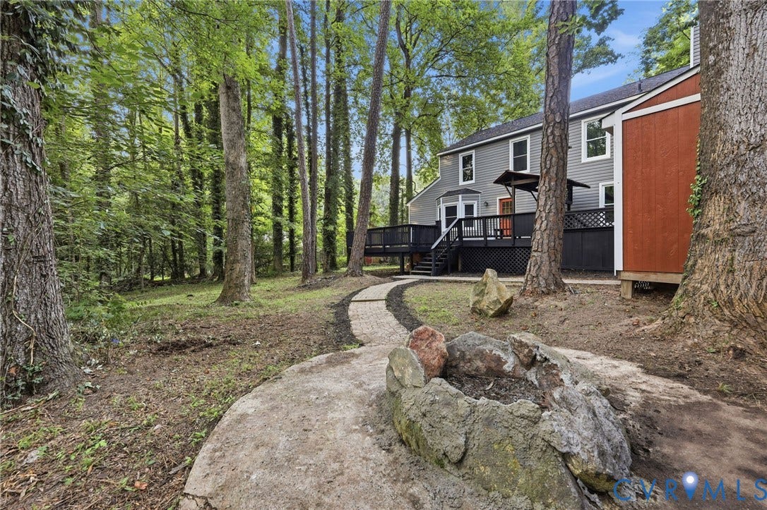 4106 Gloucestershire Street, North Chesterfield, VA 23236 Private wooded backyard with a stone fire pit, curved stone pathway, and a multi-level deck featuring black railings and lattice
