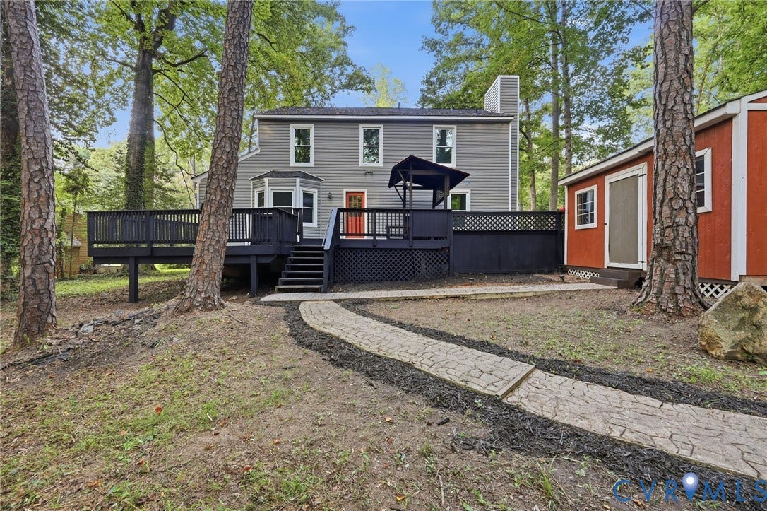 4106 Gloucestershire Street, North Chesterfield, VA 23236 Gray siding exterior with multiple windows, an expansive dark wood-finish deck, and a detached red storage shed