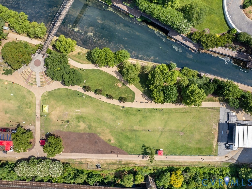 1101 Haxall Point, #U512 U510, Richmond, VA 23219 Expansive green space featuring a pedestrian bridge, a meandering river, concrete pathways, and an amphitheater with tiered seating