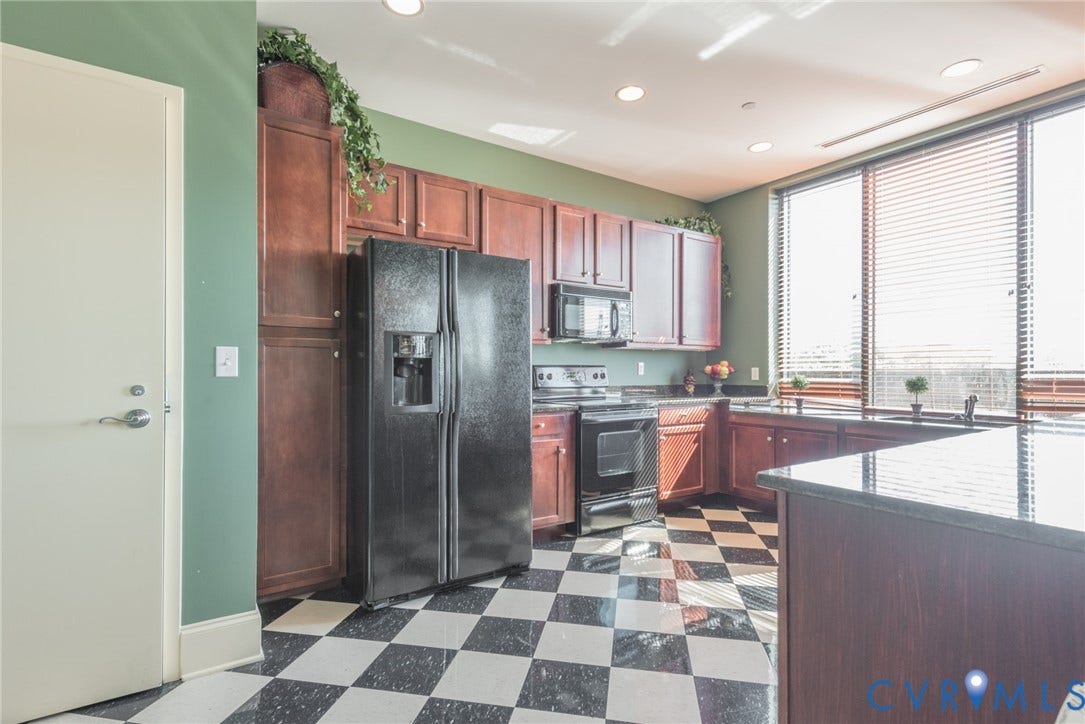 1101 Haxall Point, #U512 U510, Richmond, VA 23219 Kitchen featuring black and white checkerboard flooring, dark wood cabinetry, integrated black appliances, dark countertops, and large windows with blinds