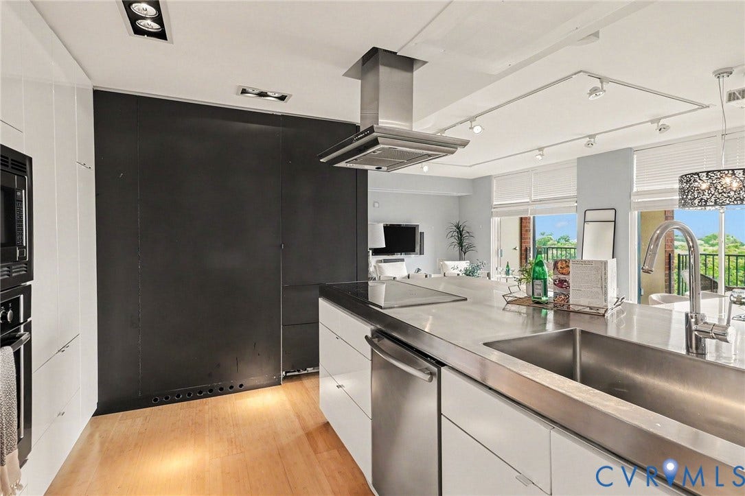 1101 Haxall Point, #U512 U510, Richmond, VA 23219 Modern kitchen featuring wood-finish flooring, white cabinetry, a stainless steel range hood, an integrated stainless steel sink, and stainless steel countertops