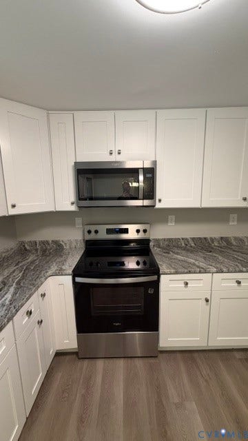 White shaker cabinetry, patterned countertops, stainless steel appliances, and wood-finish flooring