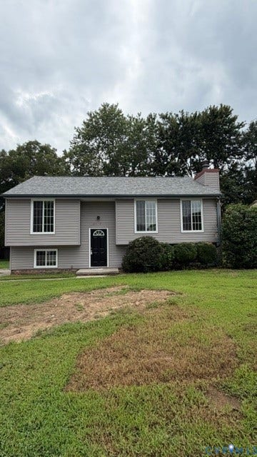 Exterior with gray siding and white trim, featuring a dark entry door and multi-pane windows