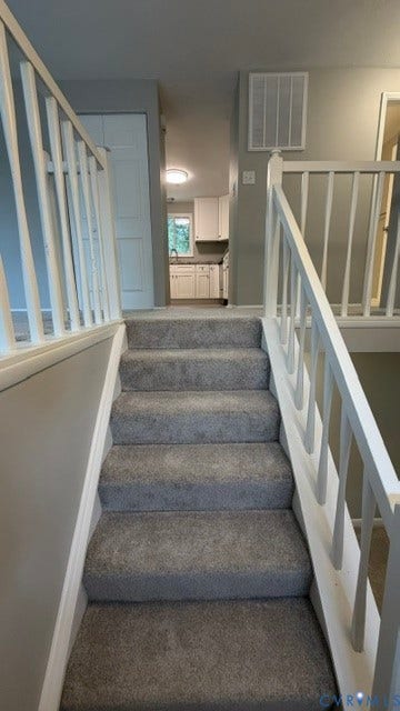 Staircase with carpeted treads and white wood railings