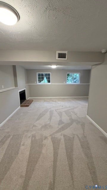 Spacious room featuring light gray carpeting, a built-in fireplace, and two windows providing natural light