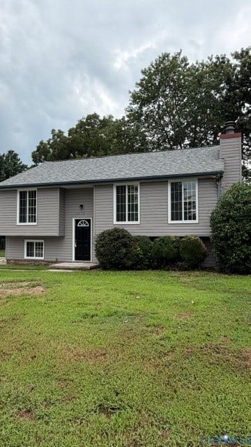 Gray siding exterior with white window frames, black entry door, and an attached chimney