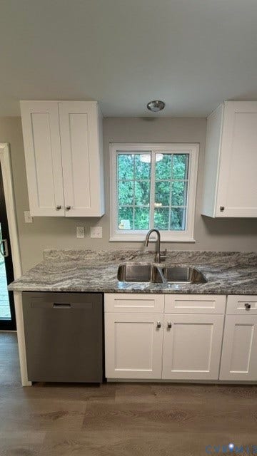 White shaker-style cabinetry with chrome hardware, dual basin stainless steel sink with a gooseneck faucet, light grey countertops, and wood-finish flooring