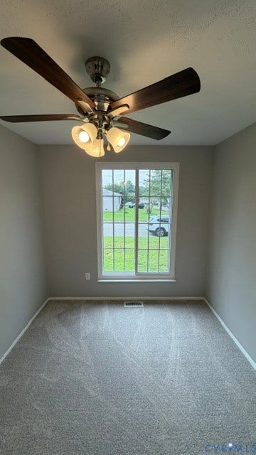 Neutral wall paint with white trim, gray carpet, a double-hung window with grilles, and a ceiling fan with integrated lighting