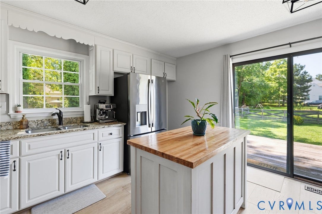 10744 Brookley Road, Glen Allen, VA 23060 White cabinetry with black hardware, granite countertops, stainless steel appliances, wood-finish kitchen island, and sliding glass door to exterior decking