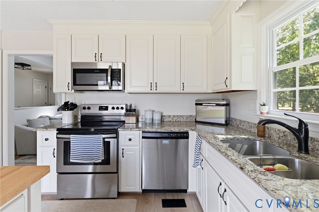 10744 Brookley Road, Glen Allen, VA 23060 White cabinetry with dark hardware, stainless steel appliances, granite countertops, and a double basin sink with a black matte faucet