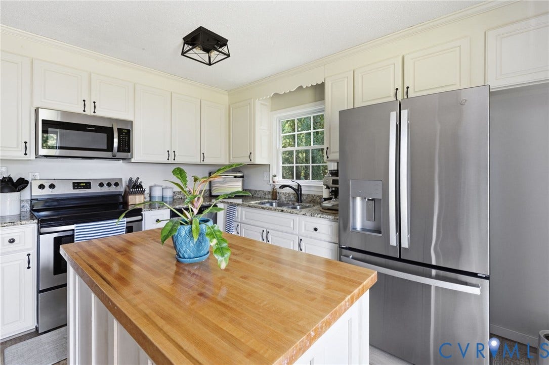 10744 Brookley Road, Glen Allen, VA 23060 White cabinetry with dark hardware, stainless steel appliances, butcher block island, window with natural light, and granite countertops