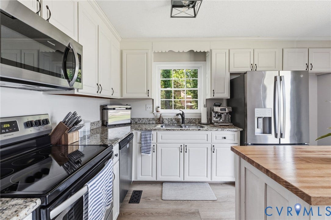 10744 Brookley Road, Glen Allen, VA 23060 White cabinetry, stainless steel appliances, speckled stone countertops, wood-finish flooring, and a natural wood island top