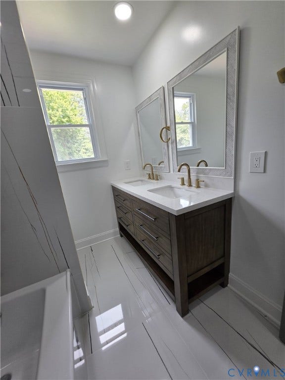 16109 Meridian Avenue, Chester, VA 23831 Elegant primary bathroom showcasing a dark wood-finish double-vanity with dual brass faucets, white quartz countertop, and large framed mirrors with integrated lighting