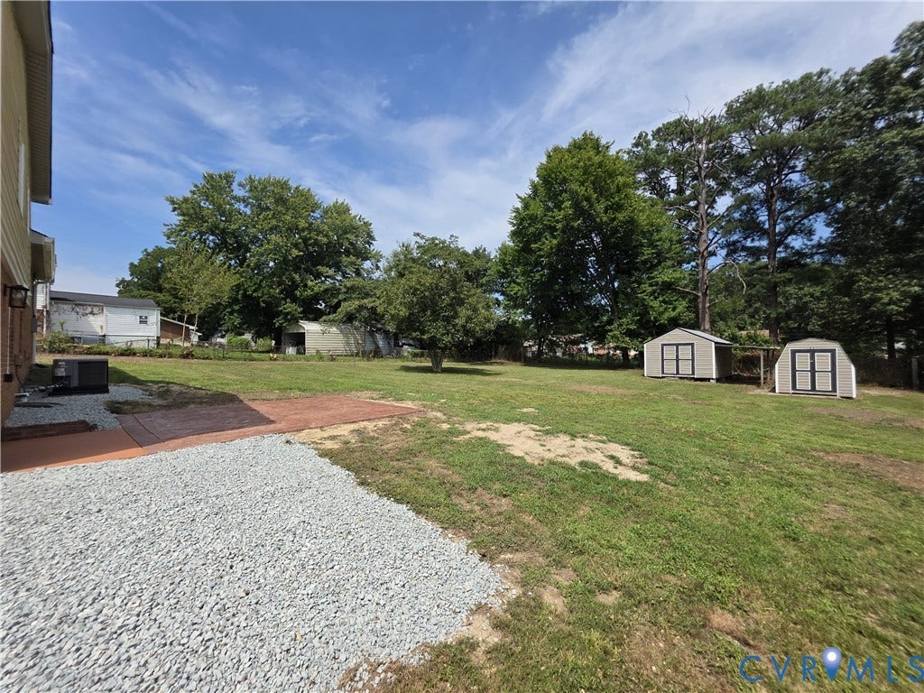 16109 Meridian Avenue, Chester, VA 23831 Expansive backyard featuring mature trees, two storage sheds, a concrete patio, and a gravel area