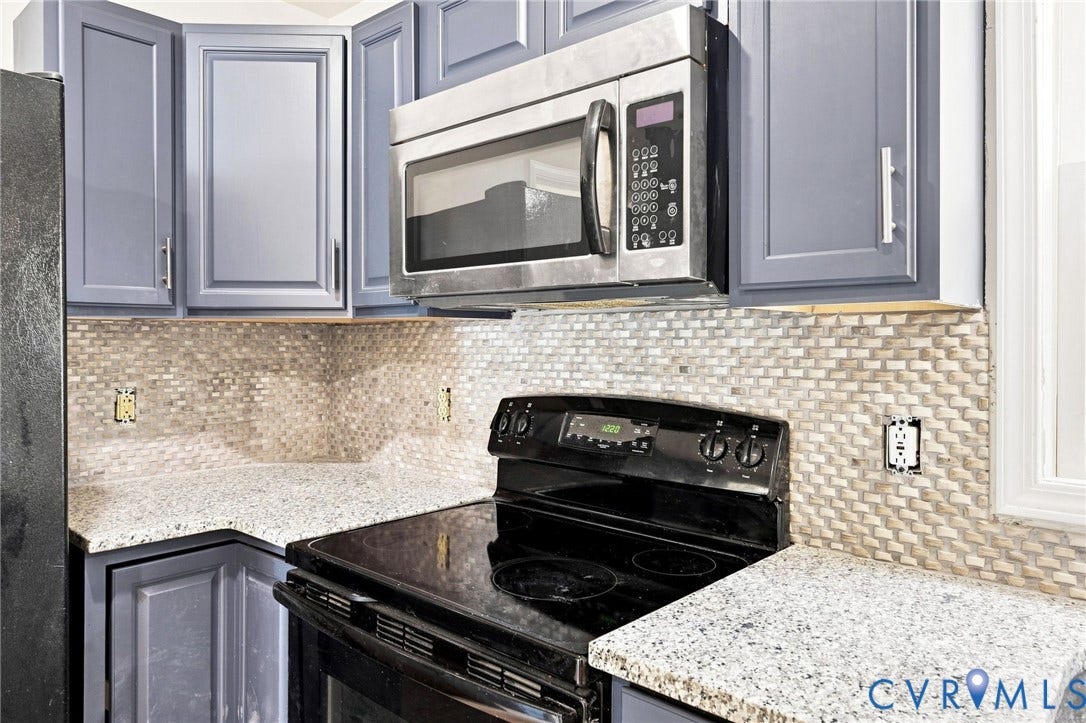 2807 Executive Drive, John Tyler Woods, Chesterfield, VA 23831 Blue cabinetry with brushed nickel hardware, light speckled countertops, stainless steel microwave, and mosaic tile backsplash