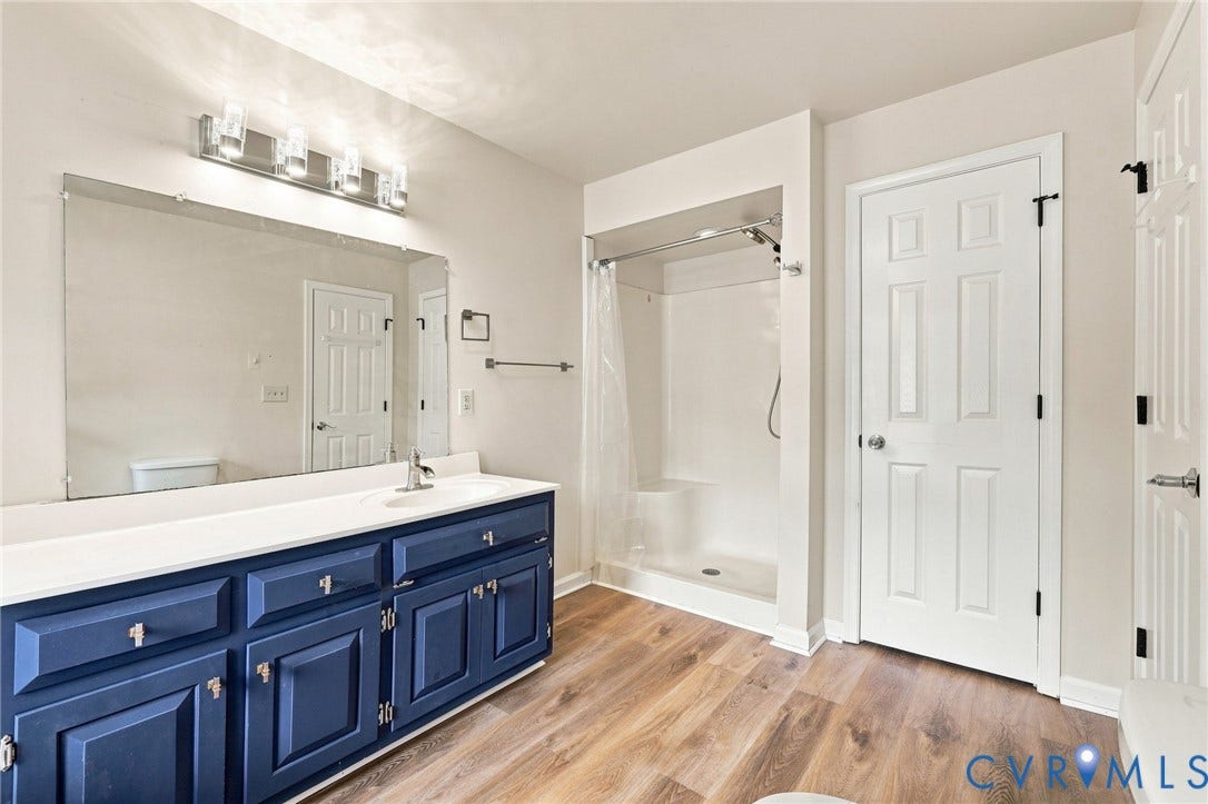 2807 Executive Drive, John Tyler Woods, Chesterfield, VA 23831 Double vanity with navy cabinetry and white countertop, wood-finish flooring, and a white shower stall