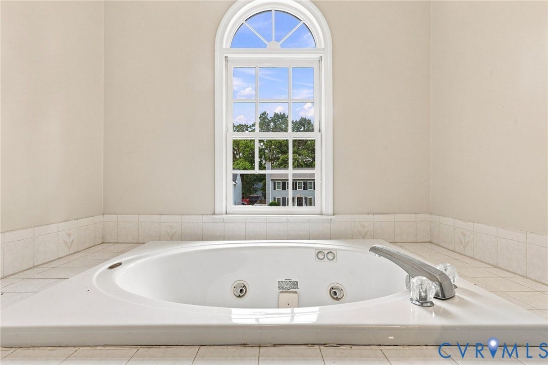 2807 Executive Drive, John Tyler Woods, Chesterfield, VA 23831 Built-in soaking tub with a tiled surround, arched window, and clear faucet handles