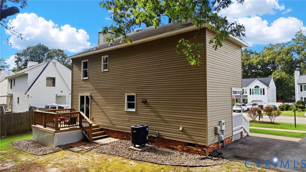 2807 Executive Drive, John Tyler Woods, Chesterfield, VA 23831 Two-story exterior with light brown siding, a ground-level wood deck with stairs, a paved driveway, and mature landscaping