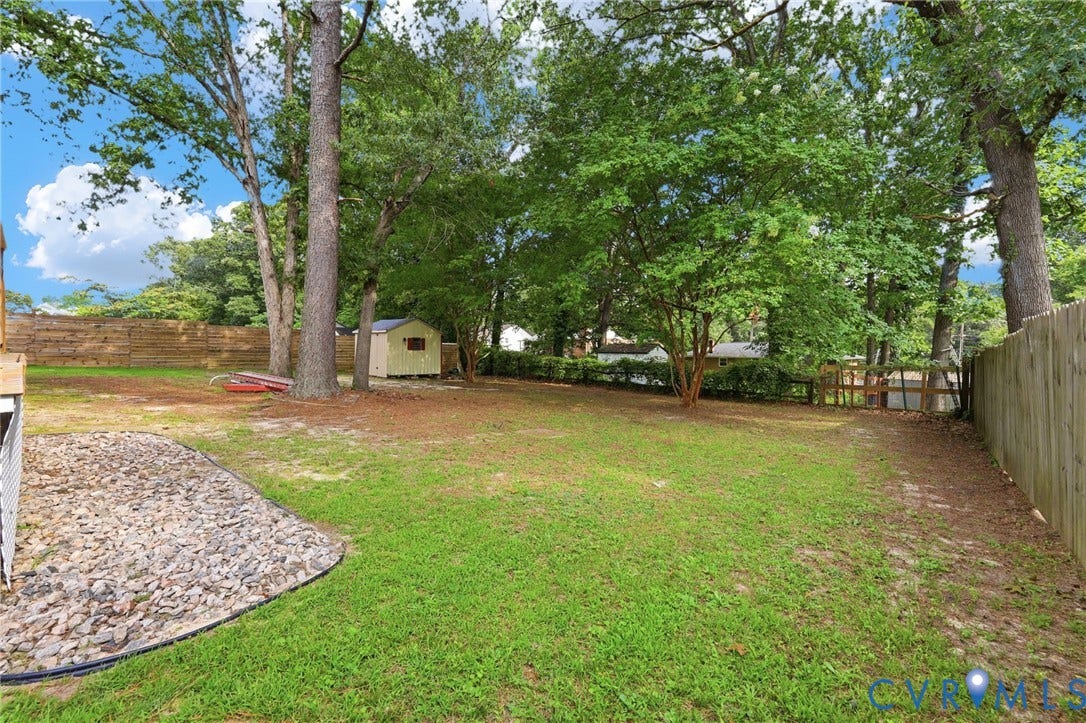 2807 Executive Drive, John Tyler Woods, Chesterfield, VA 23831 Expansive backyard with a manicured lawn, mature trees, wood privacy fencing, a gravel landscaping area, and a storage shed