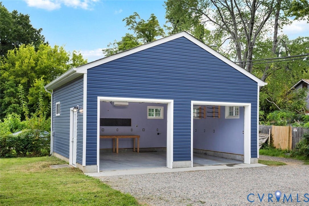 Detached two-car garage with blue siding, a side entry door, and a white trim finish