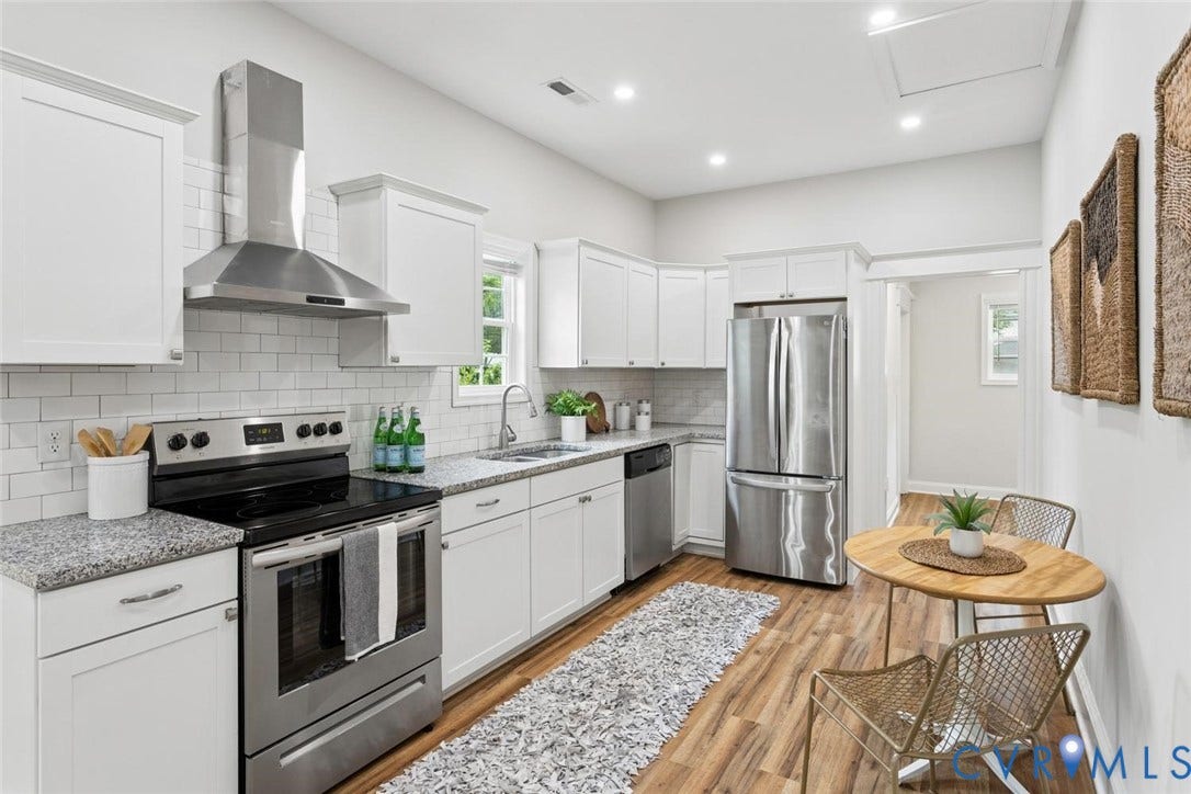 White shaker cabinetry with stainless steel appliances, granite countertops, subway tile backsplash, and wood-finish flooring