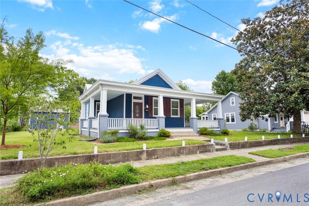 Blue exterior siding with white trim, covered front porch, white porch railing, and concrete steps