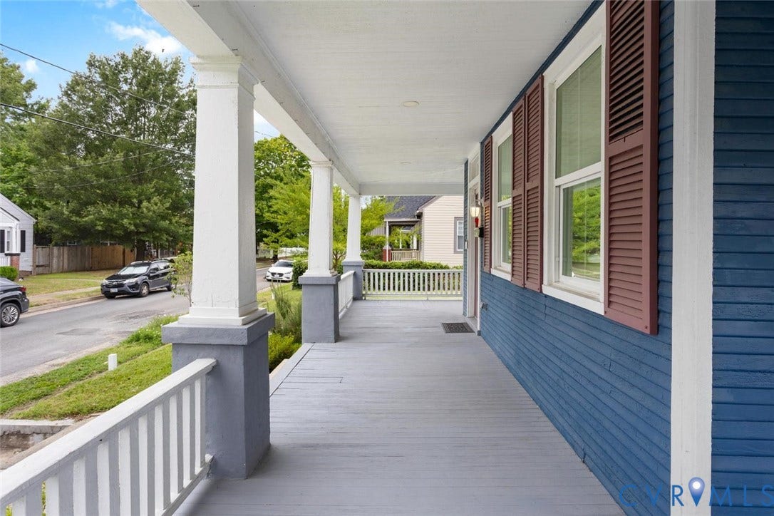 Expansive covered porch featuring a painted wood floor, white column supports, and a white railing