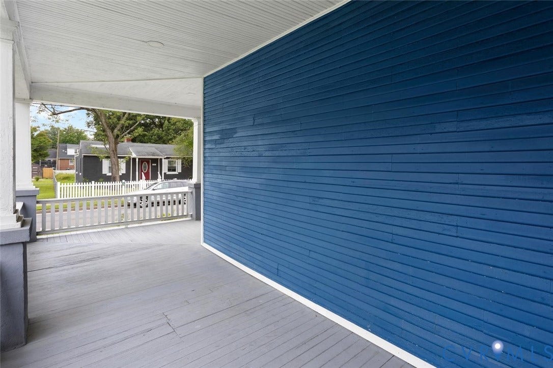 Covered porch with wood-finish flooring, white railing, and blue siding