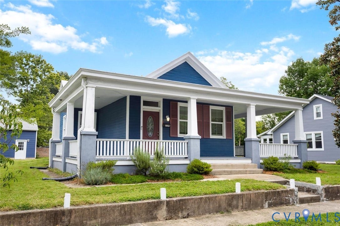 Blue exterior with white trim, covered front porch, red entry door, white porch railing, and concrete steps