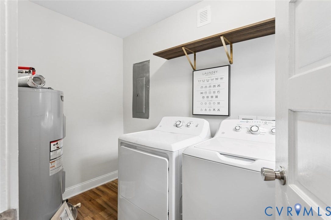 Dedicated laundry room featuring side-by-side washer and dryer appliances, wood-finish flooring, white cabinetry with upper shelving, wall-mounted drying rack, and a water heater for convenient utility access