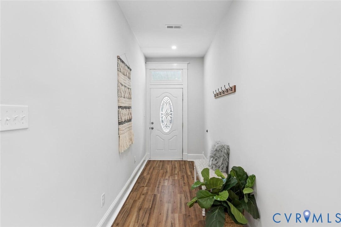 Entryway featuring wood-finish flooring, a white door with an oval-shaped decorative glass insert, and a transom window