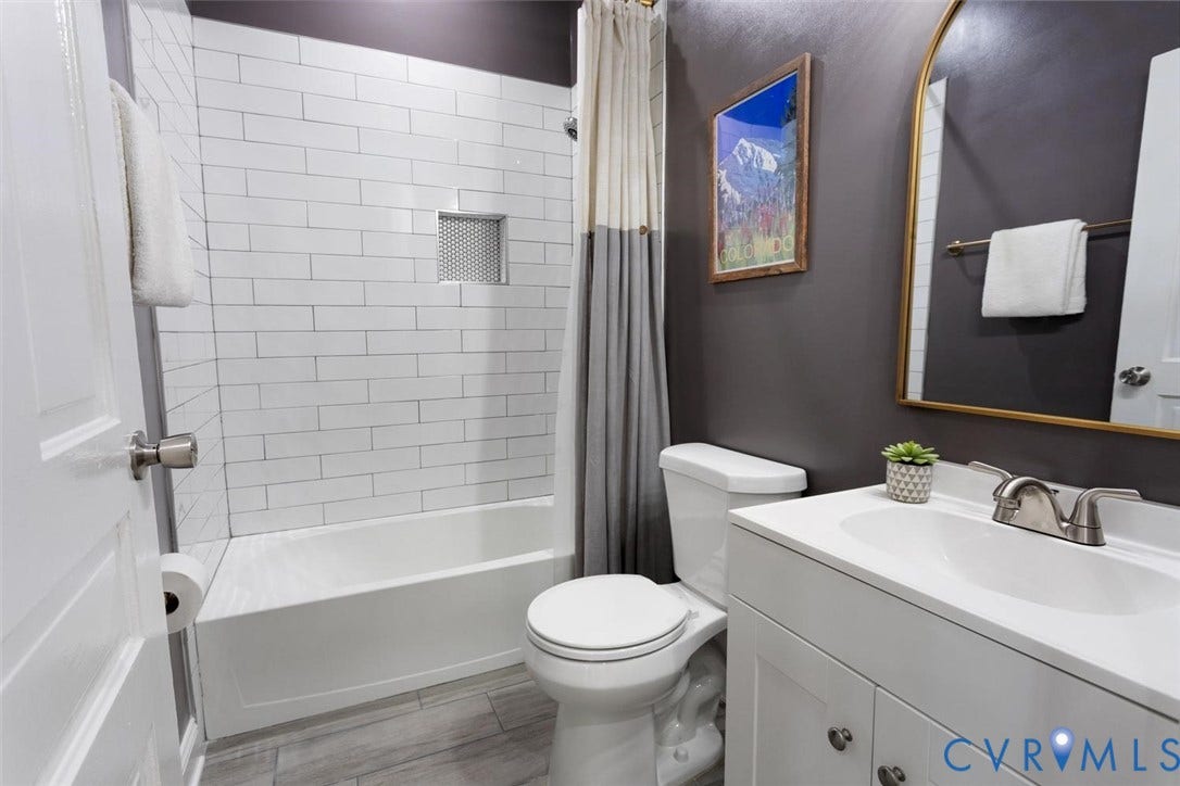 Bathroom featuring a white subway tile shower surround with a recessed niche, a white tub, and a white vanity with an integrated sink