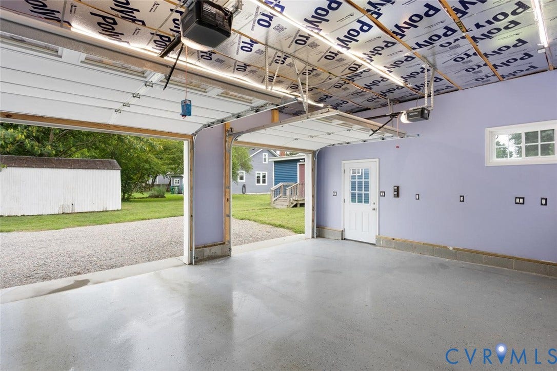 Finished garage space featuring light gray epoxy flooring, white paneled door with window inserts, and a white-framed window