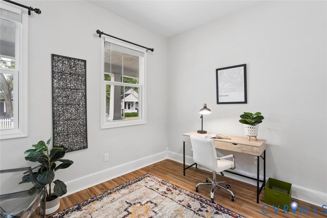 Light-toned wall paint, white trim, wood-finish flooring, and multiple windows