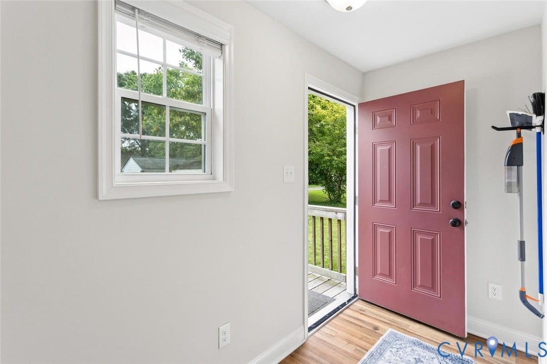Recessed panel entry door, wood-finish flooring, and white trim