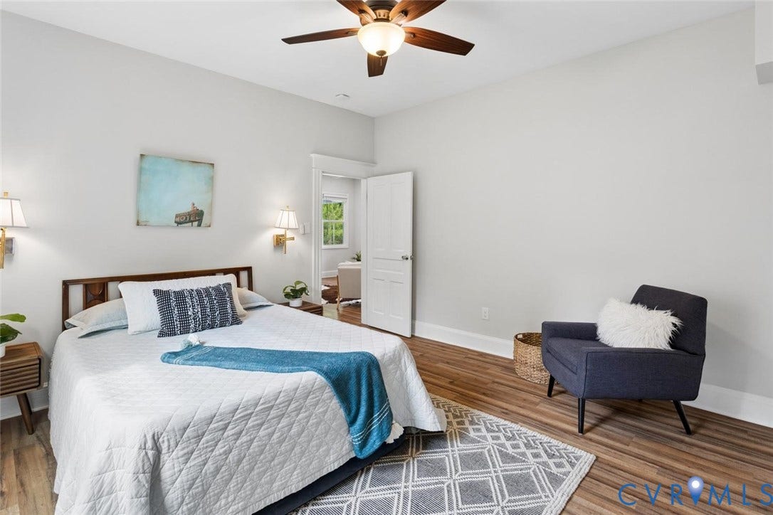 Wood-finish flooring, ceiling fan with integrated lighting, wall-mounted light fixtures, solid core door, and painted trim