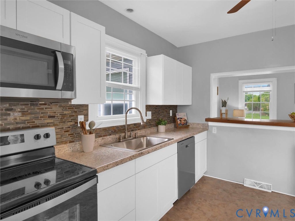 Kitchen featuring white cabinetry, a stainless steel sink, and a multi-tone tile backsplash
