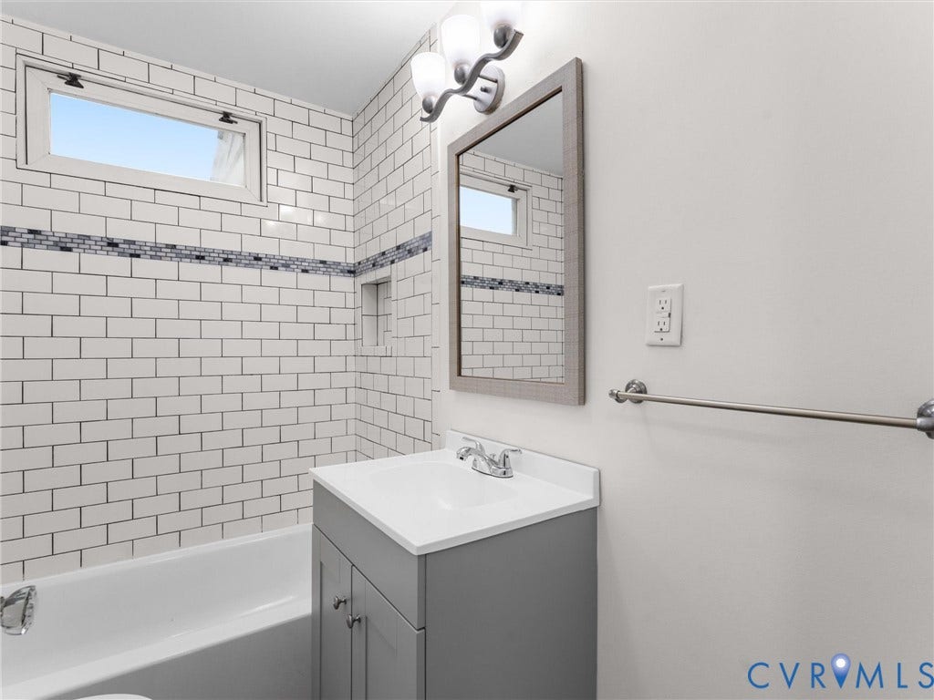 Bathroom featuring a white subway tile surround with a decorative mosaic accent band, a built-in shower niche, and an upper transom window