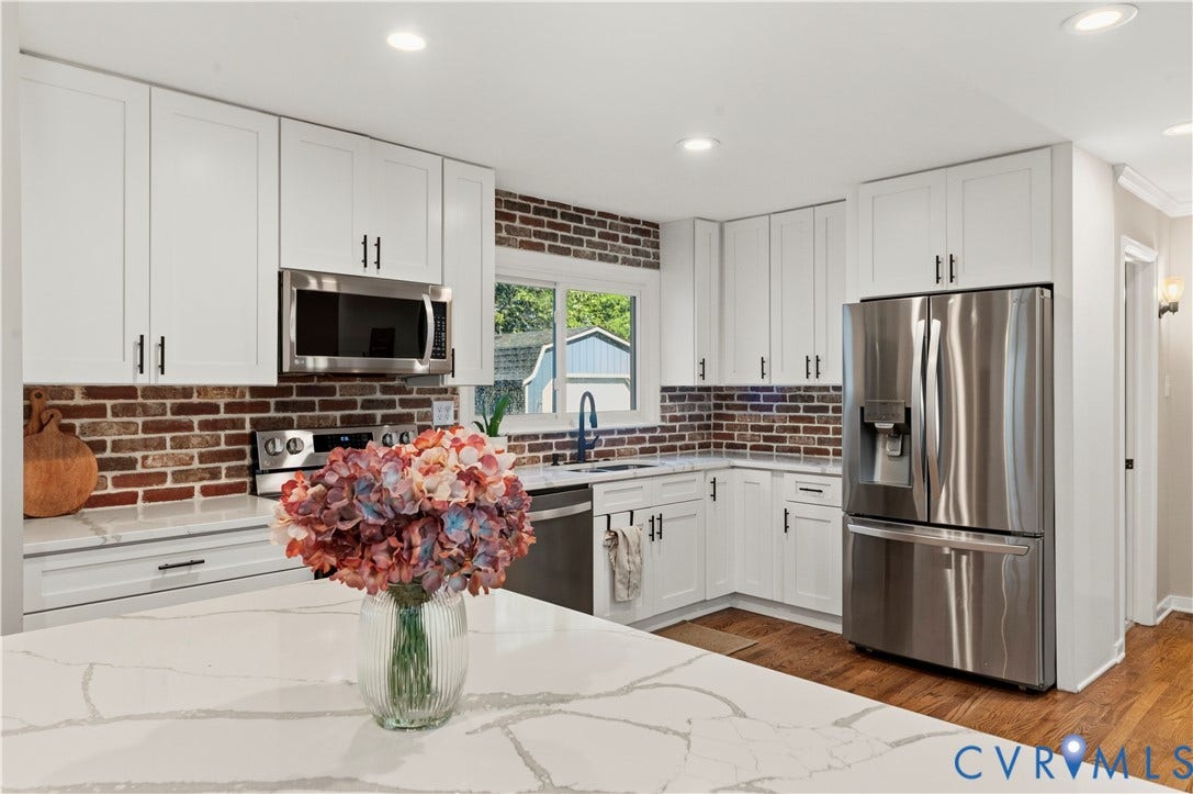 2016 Wrens Nest Road, Settlers Landing, Richmond, VA 23235 White shaker cabinetry, stainless steel appliances, brick backsplash, wood-finish flooring, and a stone countertop