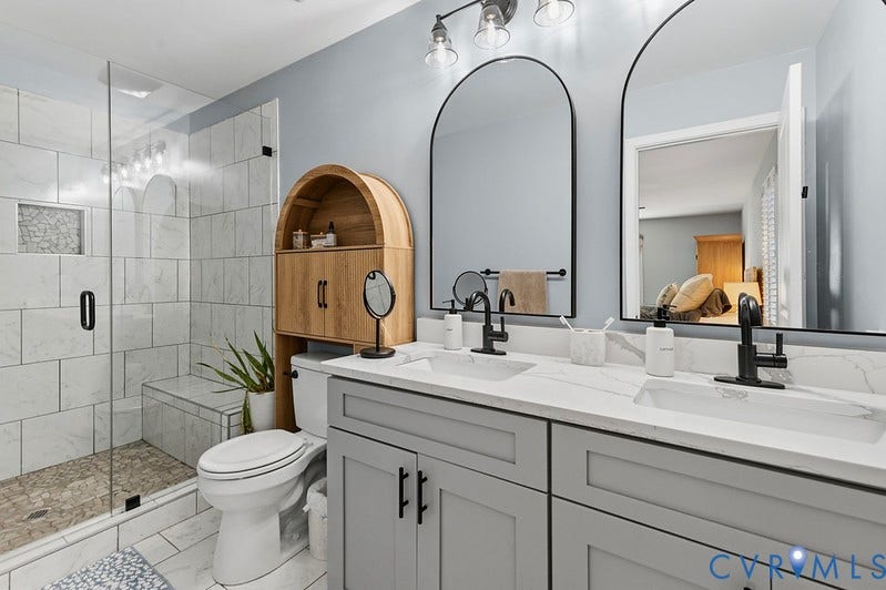 2016 Wrens Nest Road, Settlers Landing, Richmond, VA 23235 Dual arched mirrors, a spacious double vanity with under-counter storage, a large glass-enclosed shower with a built-in bench, and a tiled shower niche